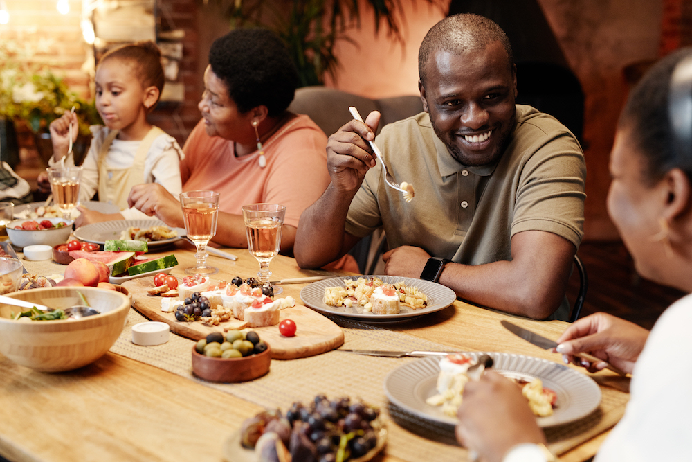 Glad familj som äter middag med fokus på en man som ler mot en familjemedlem.