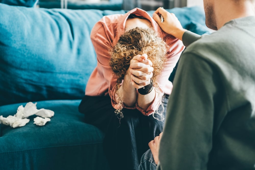 Woman sitting on sofa and crying in article about abuse.