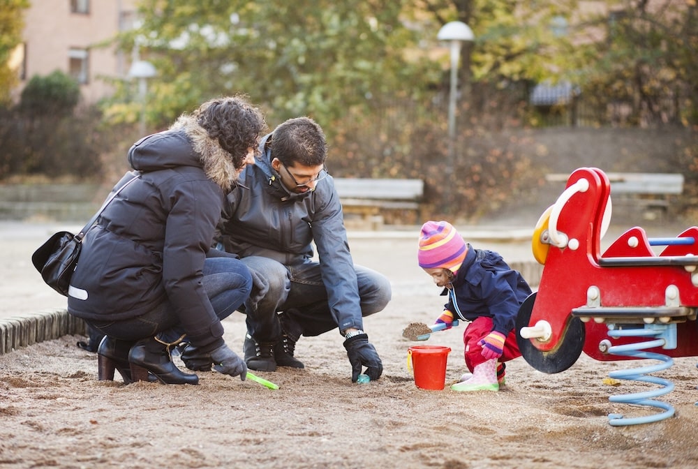 Family playing with child on playground in article about swedish citizenship for children